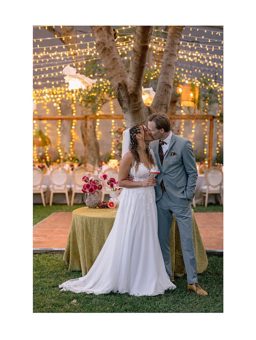 Couple sharing a kiss under wedding fairy lights